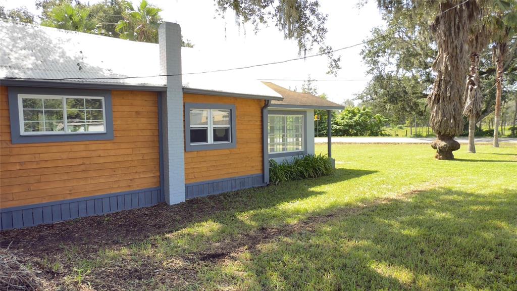 The exterior of a house features wood siding, a gray chimney, and a metal roof — 14740 JOHNS ROAD, DADE CITY, FL