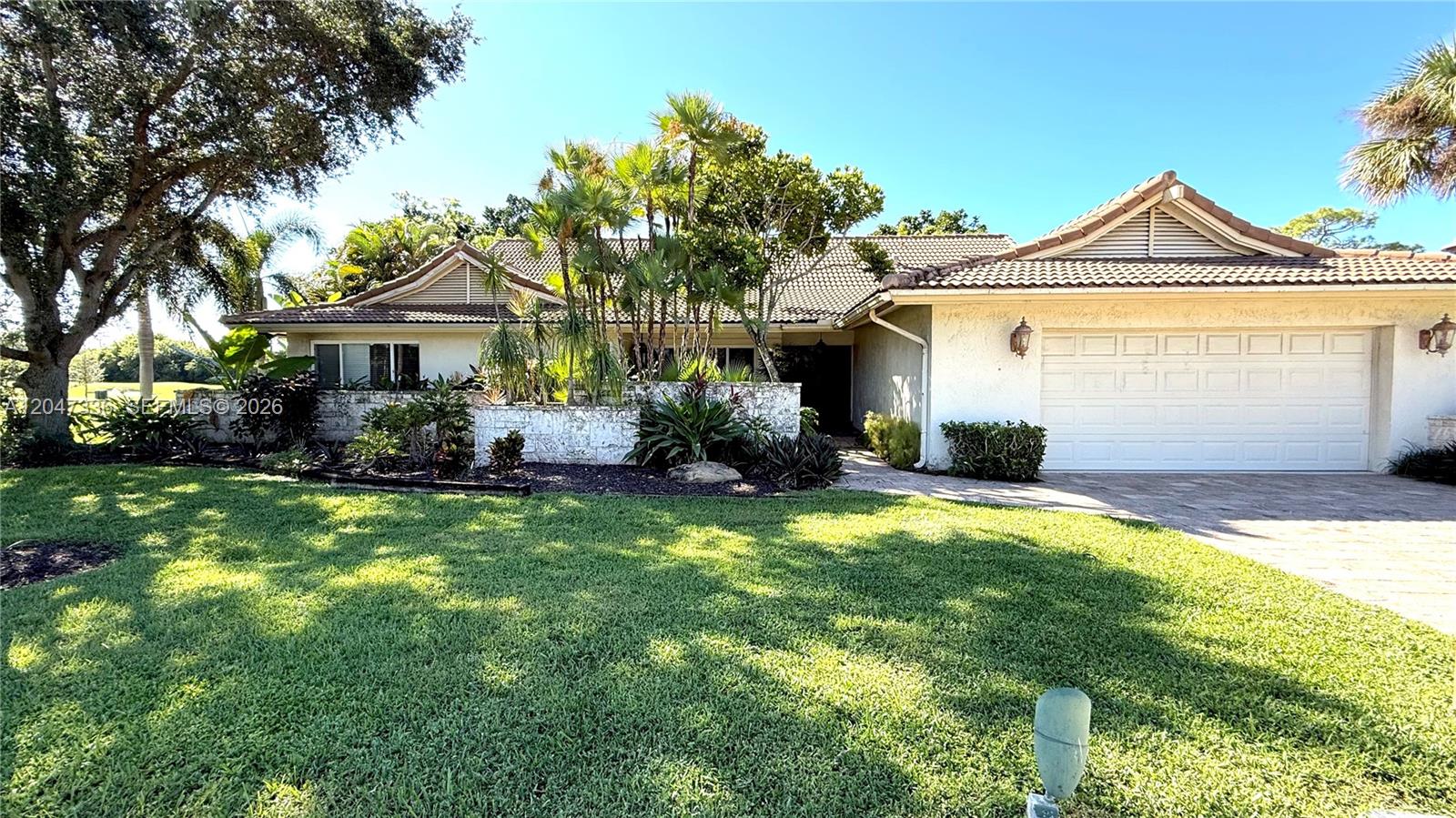 A single-story house with a white stucco exterior, a tiled roof, and a two-car garage — 10134 Boca Woods Ln # 1034, Boca Raton FL 33428, BOCA RATON, FL