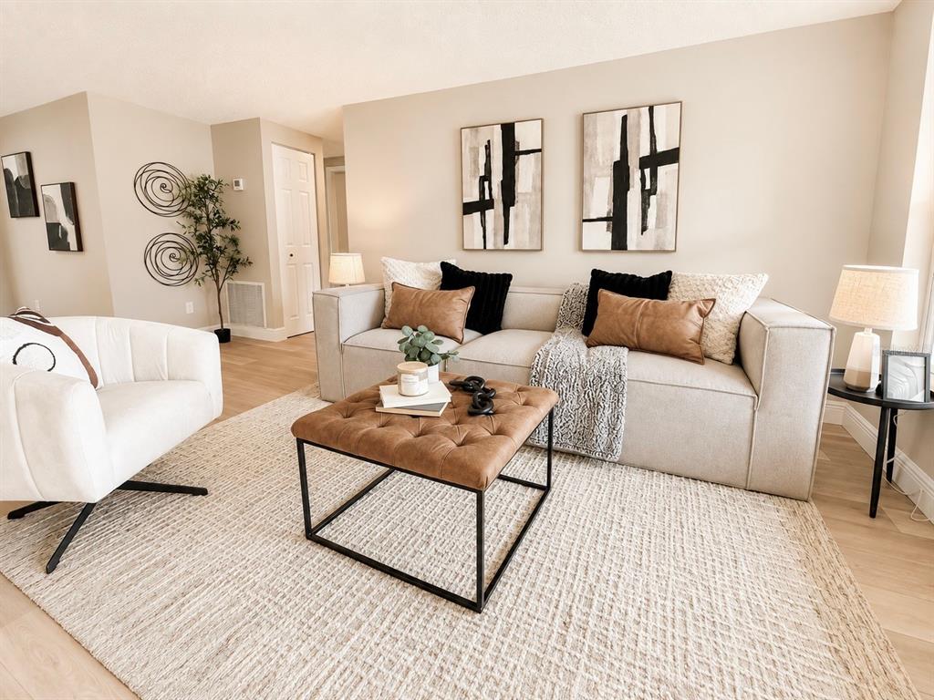 A modern living room features a beige sofa, a tufted leather ottoman, and neutral decor — 12635 NICOLE LANE, TAMPA, FL