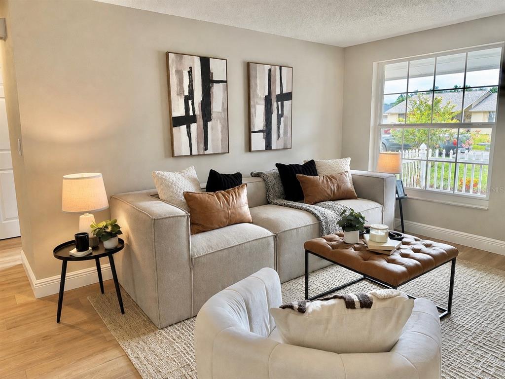 A living room features a beige sofa, leather ottoman, two abstract paintings, and a window — 12635 NICOLE LANE, TAMPA, FL