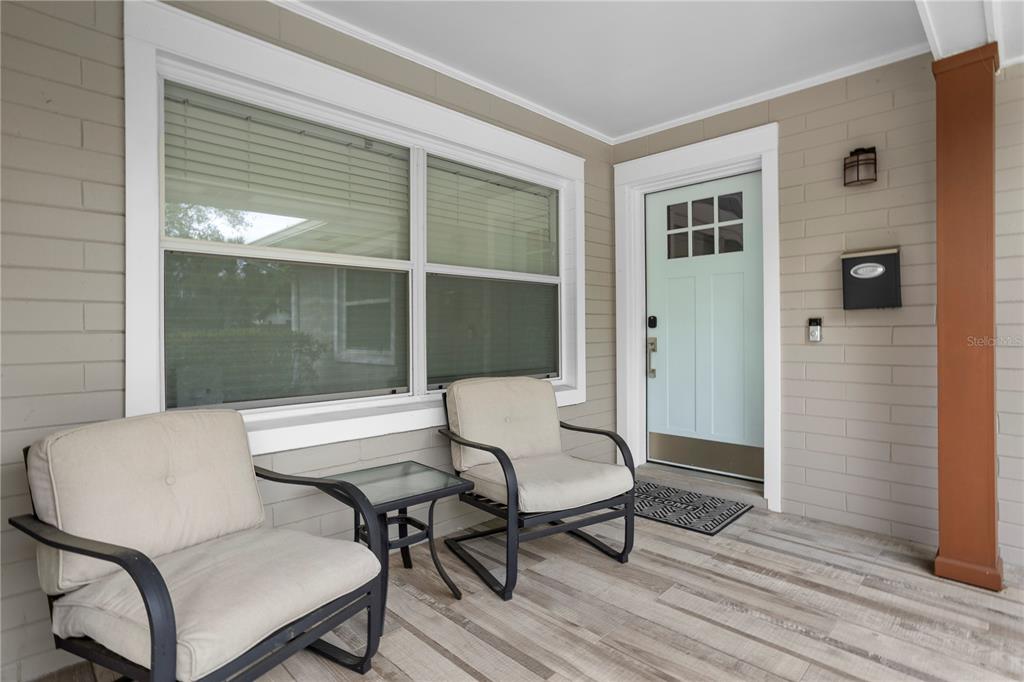 A covered front porch features light gray siding, a light blue door, and two black chairs — 2130 DELORAINE TRAIL, MAITLAND, FL