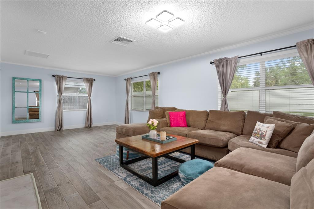 A living room features a white sofa, a round wooden coffee table, and two ottomans — 2130 DELORAINE TRAIL, MAITLAND, FL