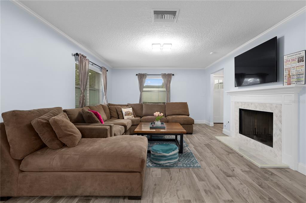 A living room features a fireplace, a white sofa, a round coffee table, and ottomans — 2130 DELORAINE TRAIL, MAITLAND, FL