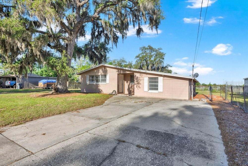 A single-story house with a concrete driveway and a large oak tree in the yard — 218 DENNIS AVENUE, WINTER HAVEN, FL