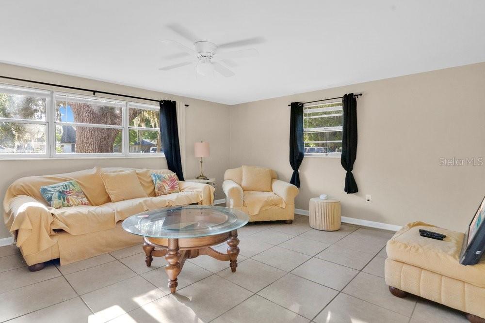 A living room with beige walls, tile flooring, a tan sofa, and two armchairs — 218 DENNIS AVENUE, WINTER HAVEN, FL
