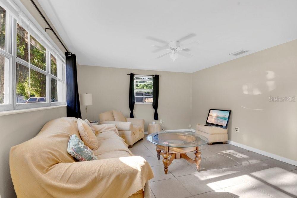 A living room features beige tile floors, a tan sofa, an armchair, and a glass-topped table — 218 DENNIS AVENUE, WINTER HAVEN, FL