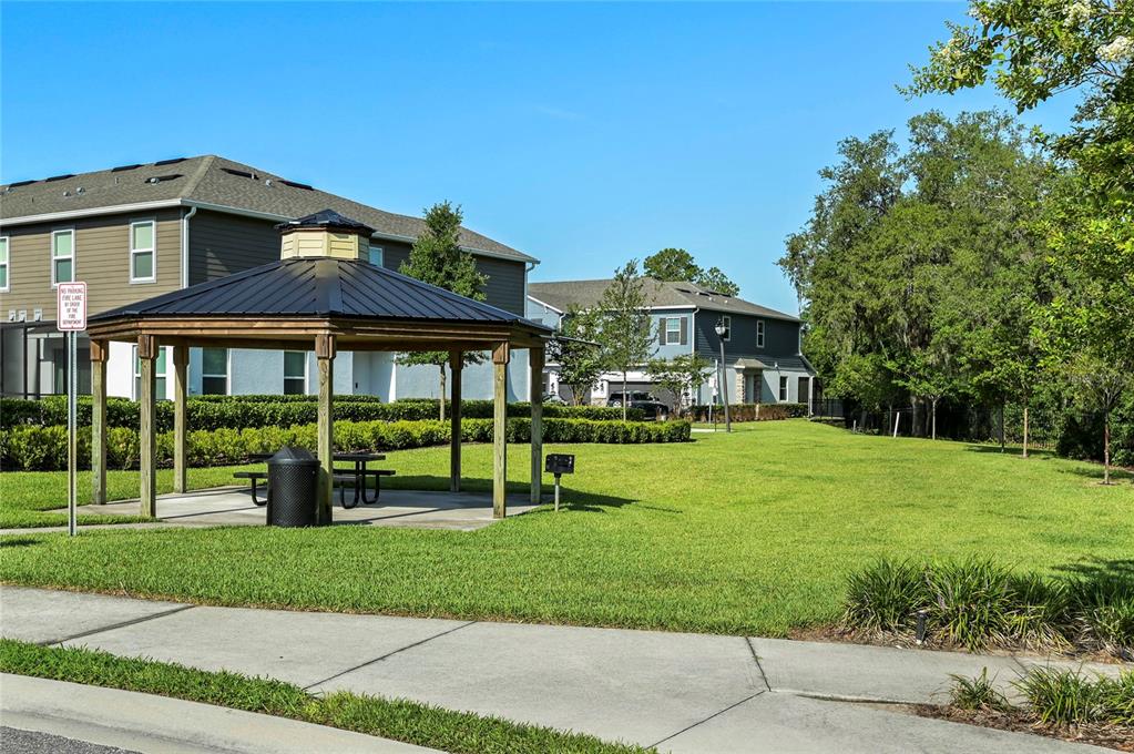 A gazebo sits on a grassy lawn in front of multi-story residential apartment buildings — 3036 PILOT HOUSE PLACE, OVIEDO, FL