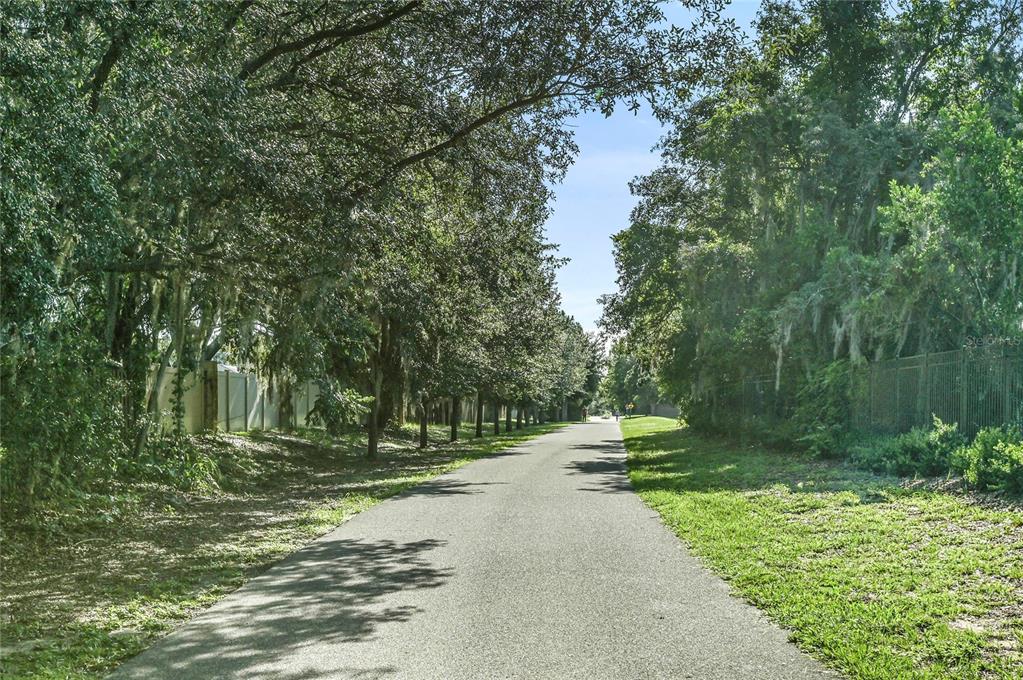 A paved path winds through a tree-lined area bordered by fences on both sides — 3036 PILOT HOUSE PLACE, OVIEDO, FL