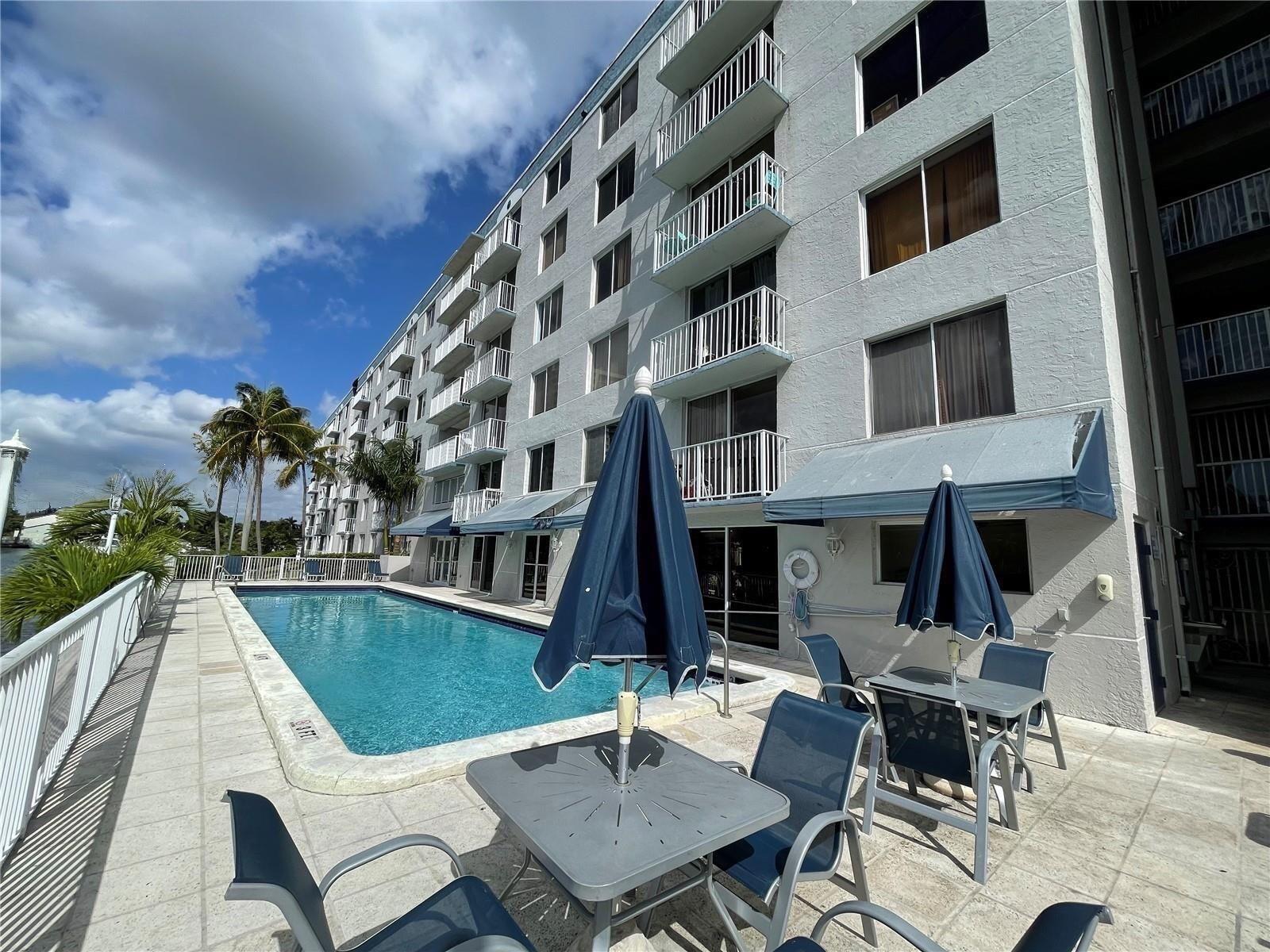 A swimming pool sits on a patio beside a multi-story apartment building with balconies — 1740 NW N River Drive # 319, Miami FL 33125, MIAMI, FL