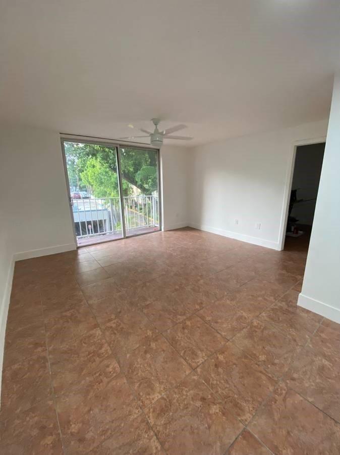 An empty room with brown tile flooring, white walls, a ceiling fan, and a sliding door — 1740 NW N River Drive # 319, Miami FL 33125, MIAMI, FL