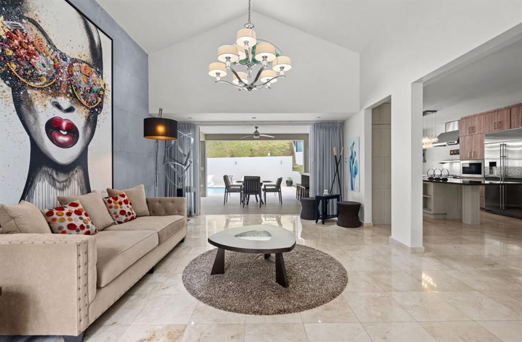 A living room with a large art piece, beige sofa, and open access to a patio — 1 ZORZAL, SAN JUAN, PR