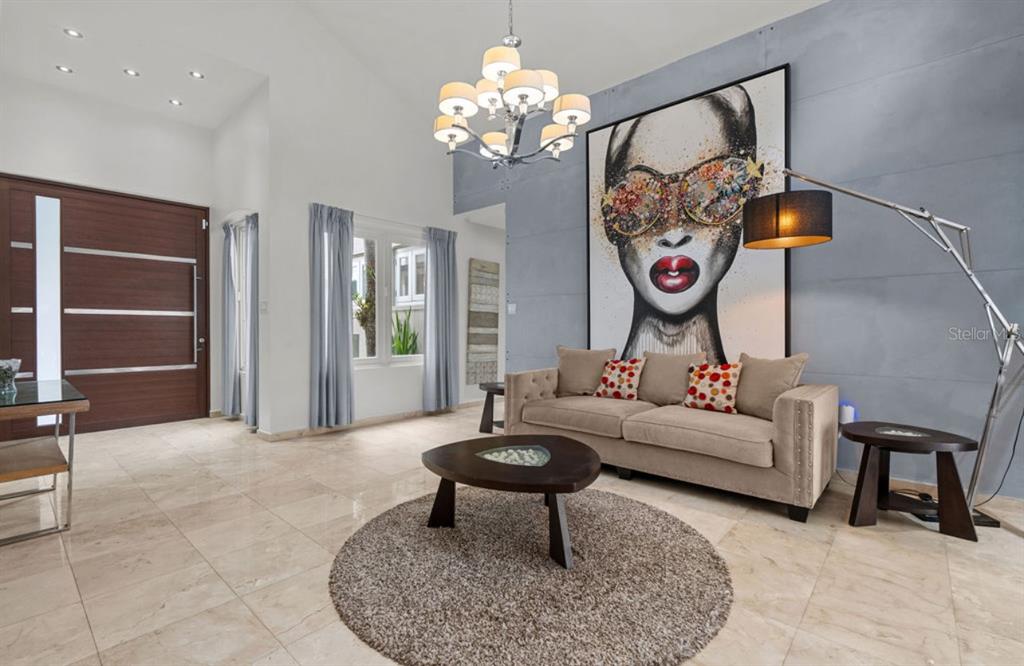 A living room features a large portrait painting, a beige sofa, and a chandelier — 1 ZORZAL, SAN JUAN, PR