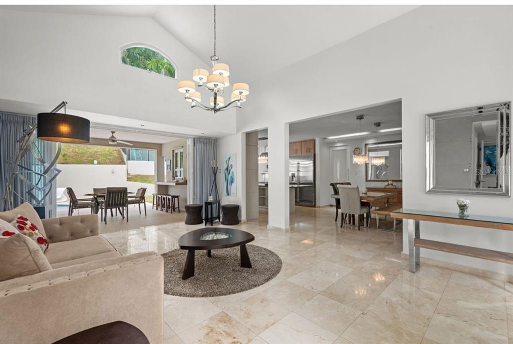 A living room with tile floors, a vaulted ceiling, and an open view to the patio — 1 ZORZAL, SAN JUAN, PR