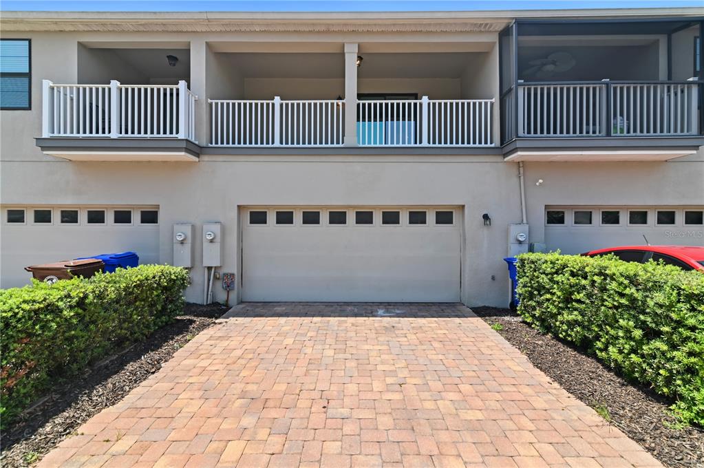 A beige building exterior features a central garage door, a paved driveway, and upper-level balconies — 2913 WINDMILL DR, KISSIMMEE, FL