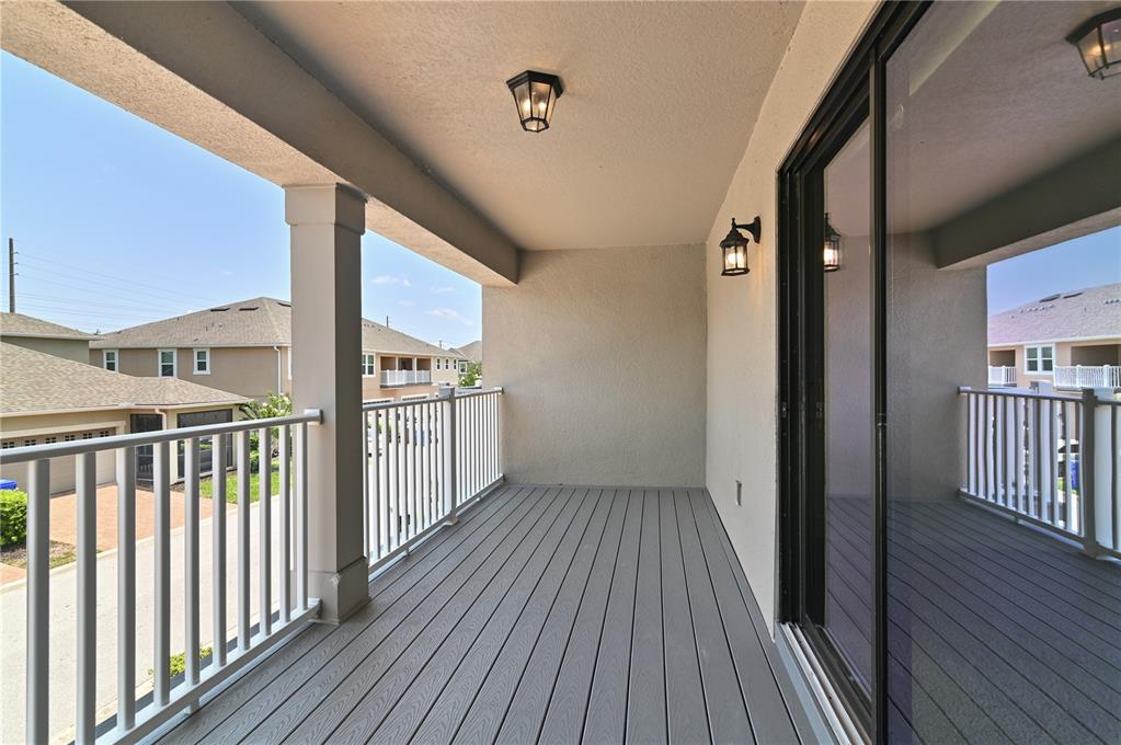 A covered balcony features gray composite decking, white railings, and wall-mounted light fixtures — 2913 WINDMILL DR, KISSIMMEE, FL