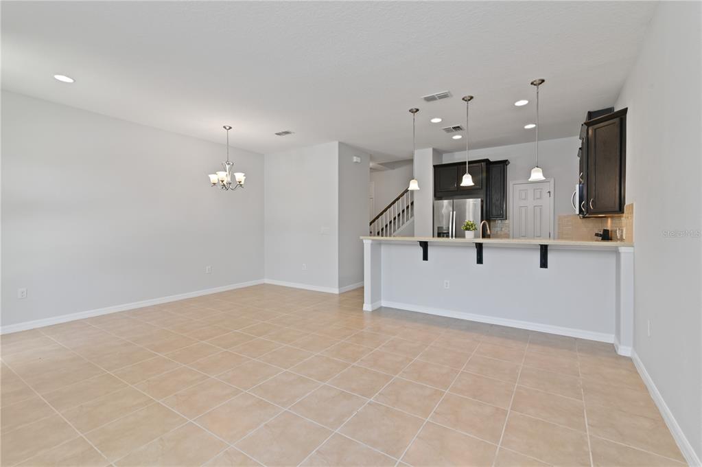 A dining area with tile flooring opens to a kitchen featuring dark cabinets and island — 2913 WINDMILL DR, KISSIMMEE, FL