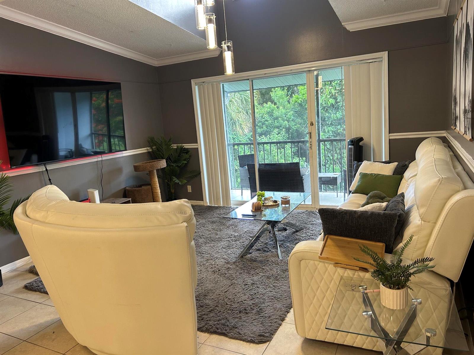 A living room features dark gray walls, white leather furniture, a glass coffee table, and balcony — 1007 Green Pine Boulevard, West Palm Beach FL 33409, WEST PALM BEACH, FL