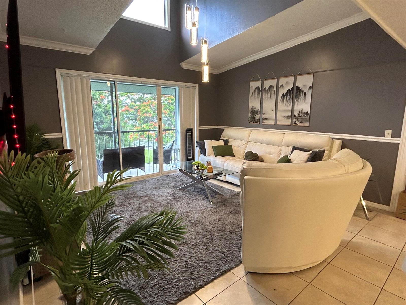 A living room features a white curved sofa, a glass coffee table, and a balcony view — 1007 Green Pine Boulevard, West Palm Beach FL 33409, WEST PALM BEACH, FL