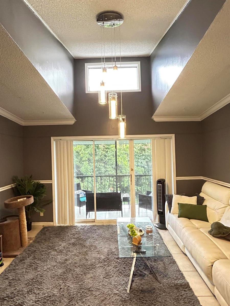 A living room features a high vaulted ceiling, a modern pendant light, and sliding glass doors — 1007 Green Pine Boulevard, West Palm Beach FL 33409, WEST PALM BEACH, FL