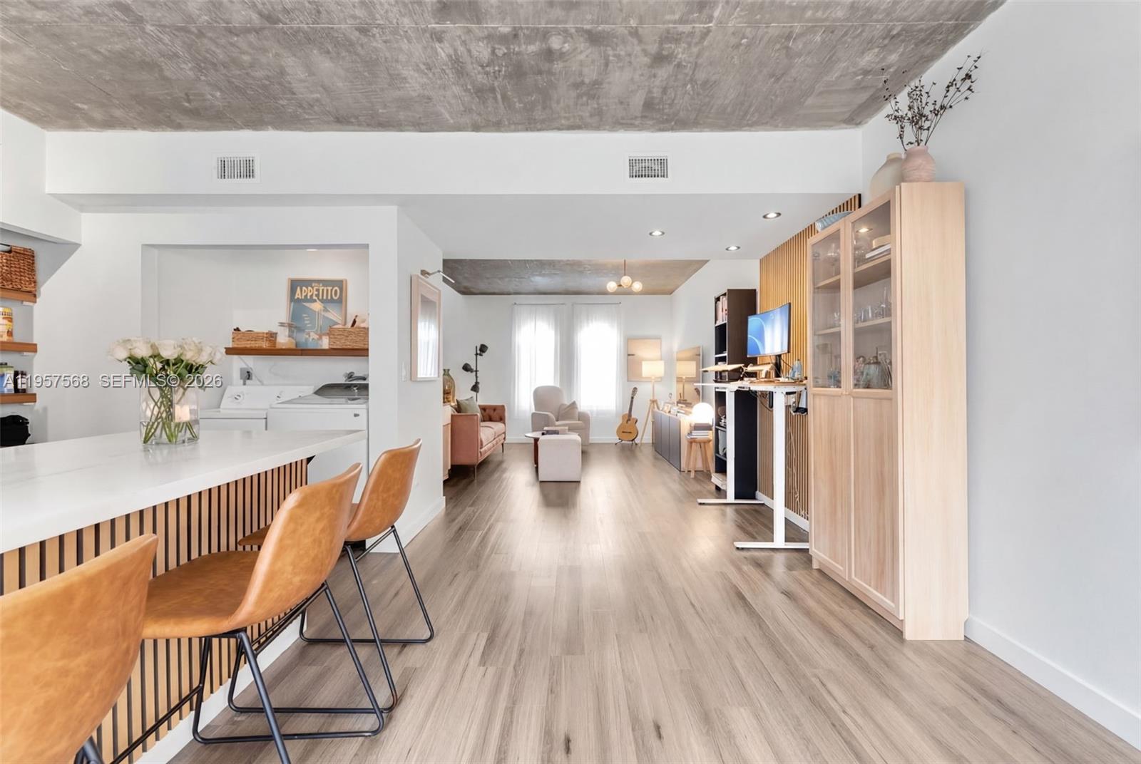 A modern open-concept living space features a kitchen island, wood-slat accents, and concrete ceilings — 5265 NW 112th Ave # 6, Doral FL 33178, DORAL, FL