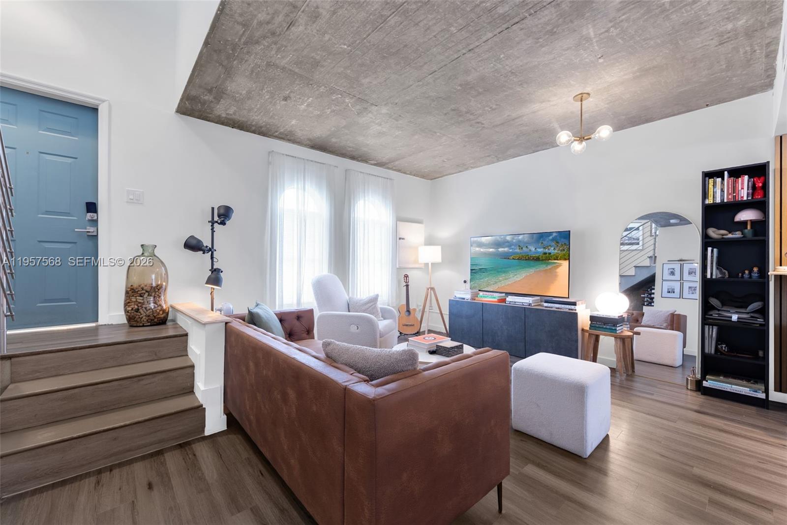 A living room features a brown leather sofa, a concrete ceiling, and a blue door — 5265 NW 112th Ave # 6, Doral FL 33178, DORAL, FL