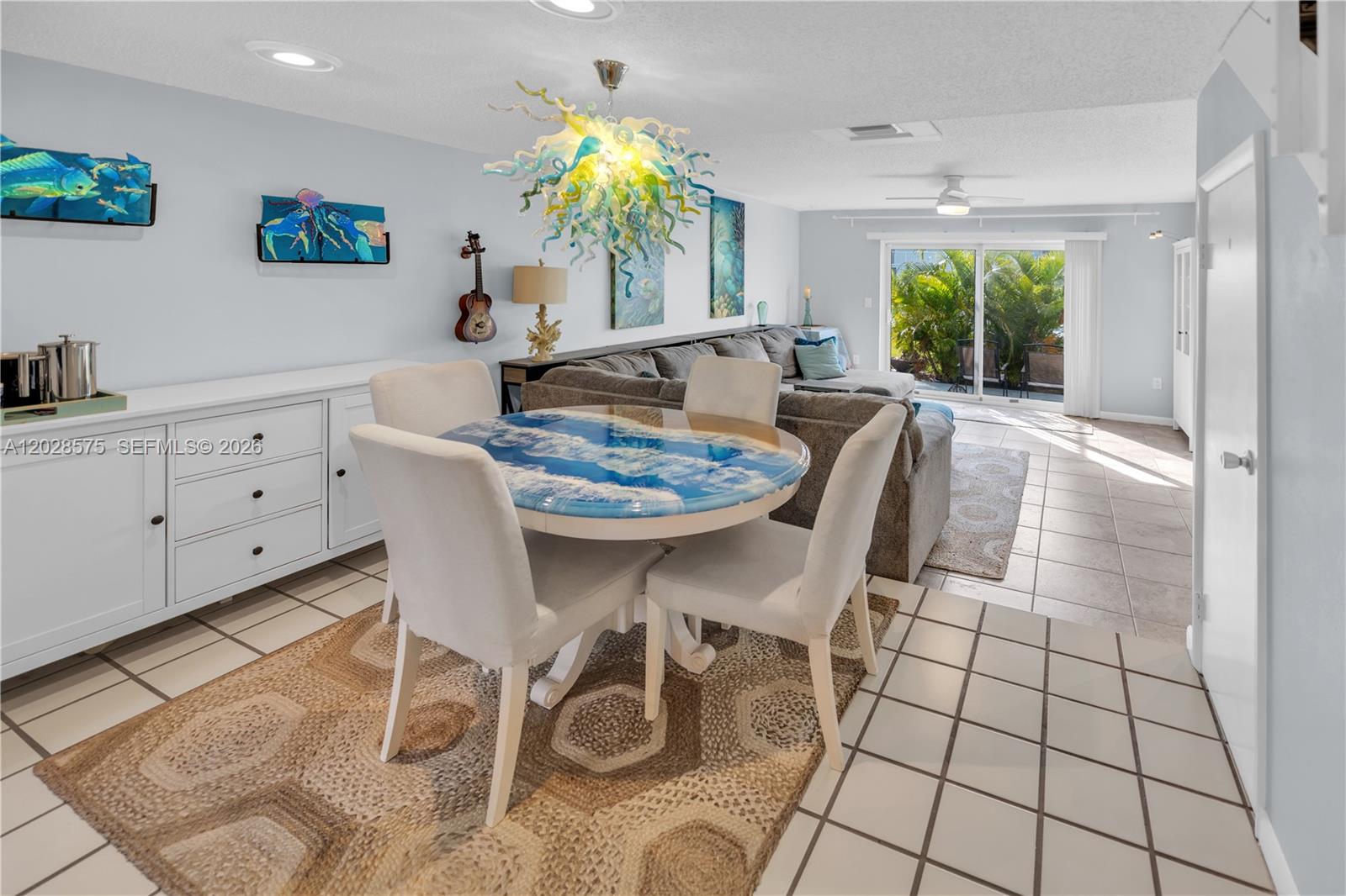 A dining area with a resin ocean-themed table sits adjacent to a living room — 40 High Point Rd # 402, Islamorada FL 33070, ISLAMORADA, FL