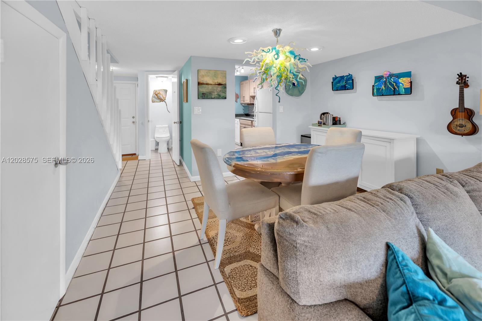 A dining area features a round resin table, upholstered chairs, and a unique glass chandelier — 40 High Point Rd # 402, Islamorada FL 33070, ISLAMORADA, FL