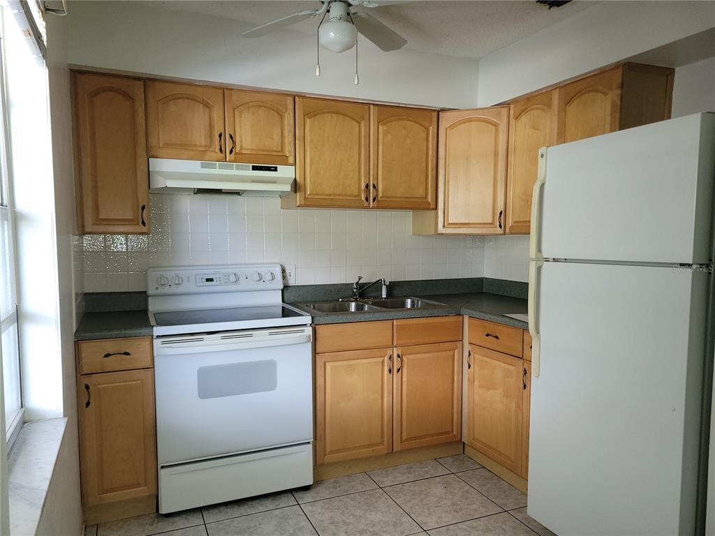 A kitchen with light wood cabinets, white appliances, a tiled backsplash, and gray countertops — 9110 VIA RECREO, NEW PORT RICHEY, FL