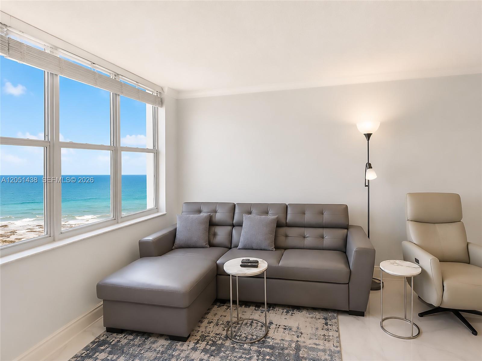 A living room features a grey sectional sofa, a beige recliner, and ocean views — 2201 S Ocean Dr # 2005, Hollywood FL 33019, HOLLYWOOD, FL