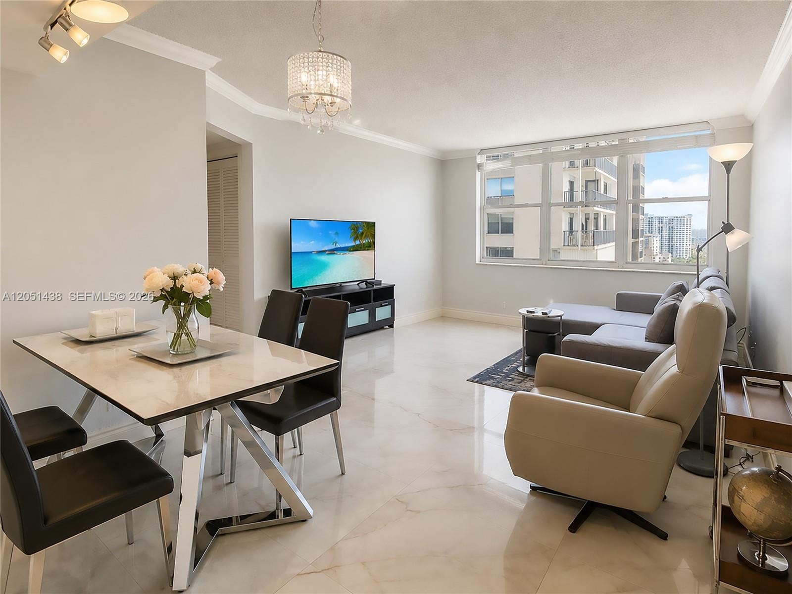 A bright living and dining area features marble floors, a chandelier, and city views — 2201 S Ocean Dr # 2005, Hollywood FL 33019, HOLLYWOOD, FL