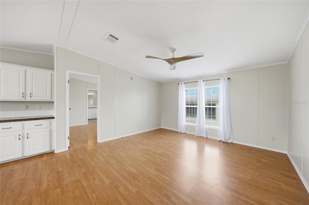 A bright living room features light wood flooring, white cabinets, and a ceiling fan — 4810 NW HIGHWAY 72 UNIT 162, ARCADIA, FL