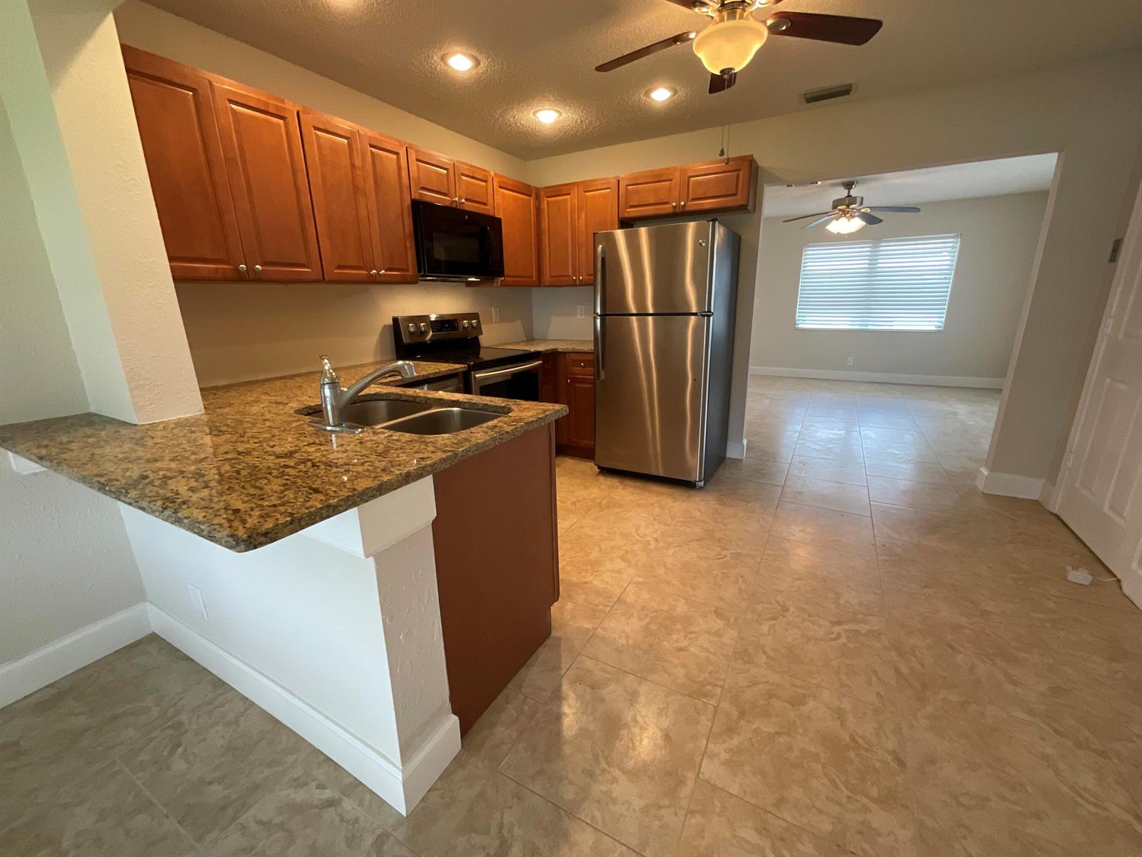 A kitchen with wood cabinets, granite countertops, stainless steel appliances, and tile flooring — 2016 SW 16th Avenue, Boynton Beach FL 33426, BOYNTON BEACH, FL