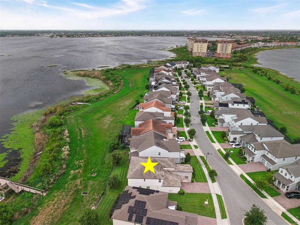An aerial view shows a residential neighborhood with houses situated along a large lake — 7446 ALPINE BUTTERFLY LANE, ORLANDO, FL