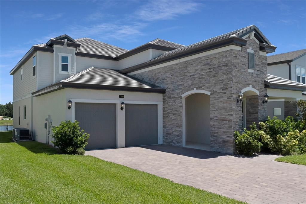 A two-story house with a stone facade, a two-car garage, and a paved driveway — 7446 ALPINE BUTTERFLY LANE, ORLANDO, FL