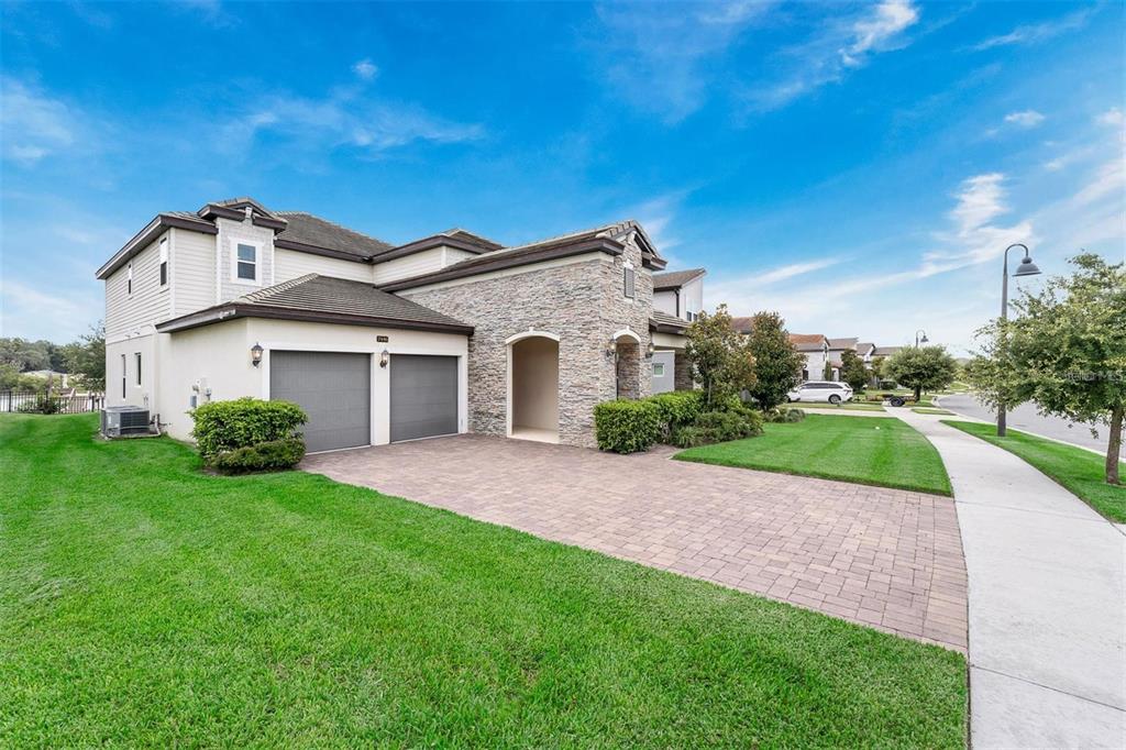 A two-story suburban house with a stone facade, a two-car garage, and a paved driveway — 7446 ALPINE BUTTERFLY LANE, ORLANDO, FL