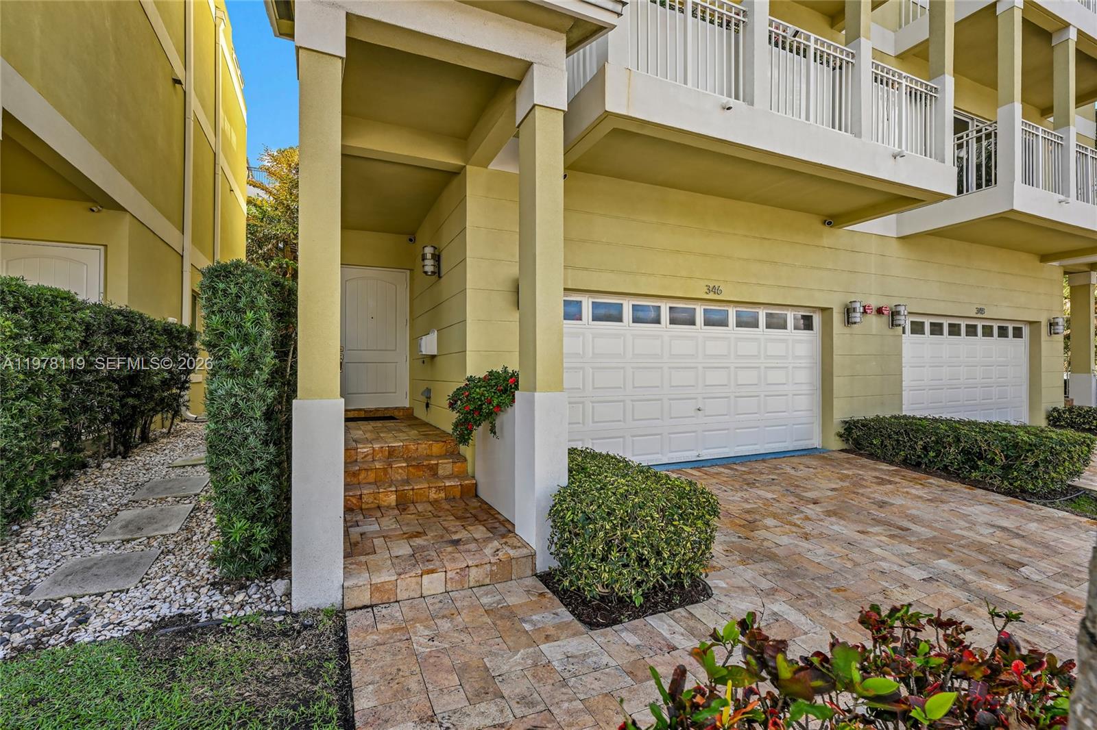 The exterior view shows a yellow townhouse with a white garage door and stone-paved entrance — 346 Elm St # 10, Hollywood FL 33019, HOLLYWOOD, FL