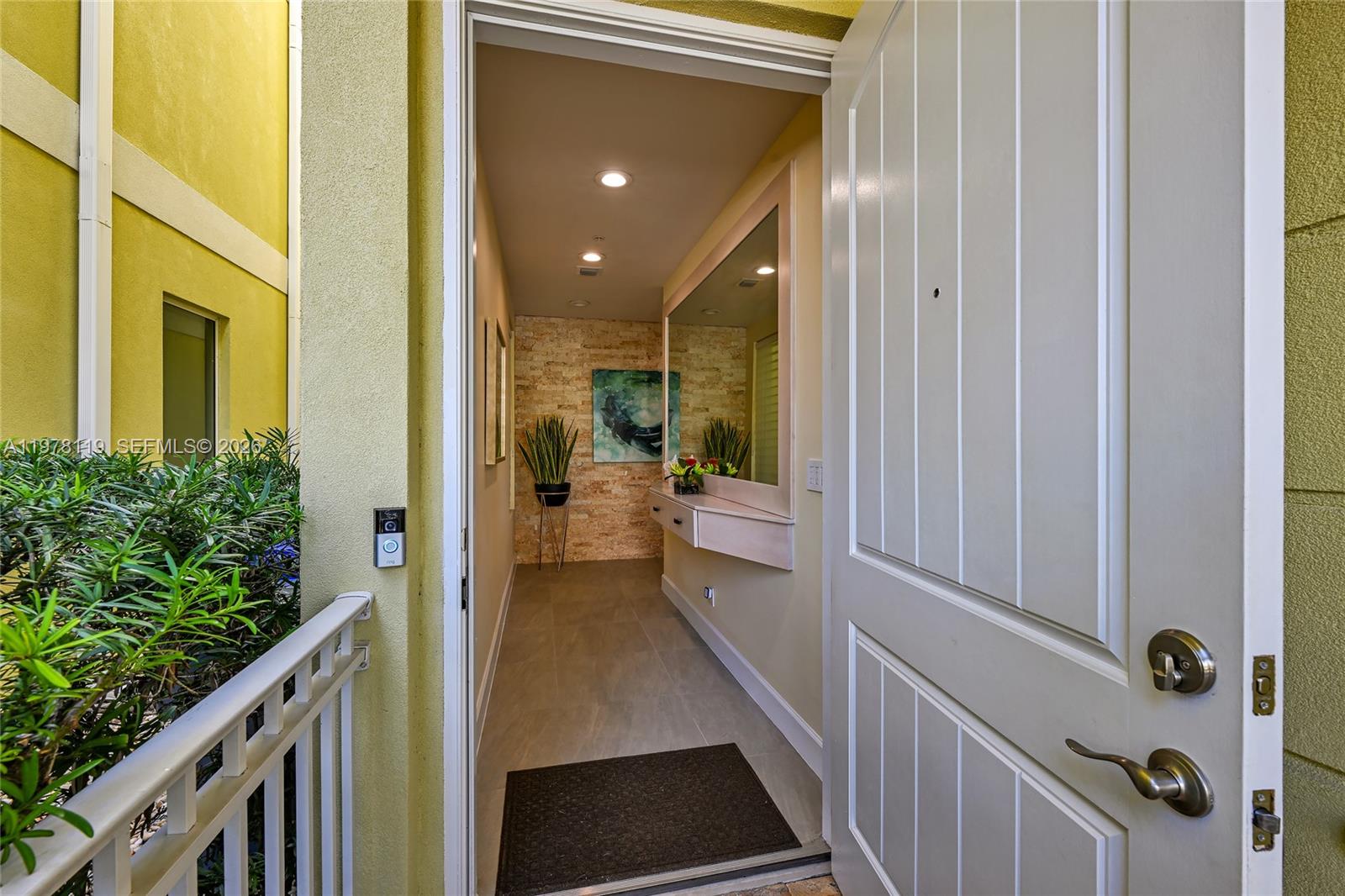 An open door reveals an entryway with a stone accent wall, mirror, and console table — 346 Elm St # 10, Hollywood FL 33019, HOLLYWOOD, FL