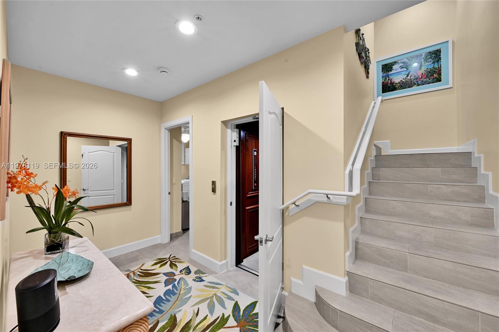 An entryway features a staircase, an elevator, a mirror, and a patterned rug — 346 Elm St # 10, Hollywood FL 33019, HOLLYWOOD, FL