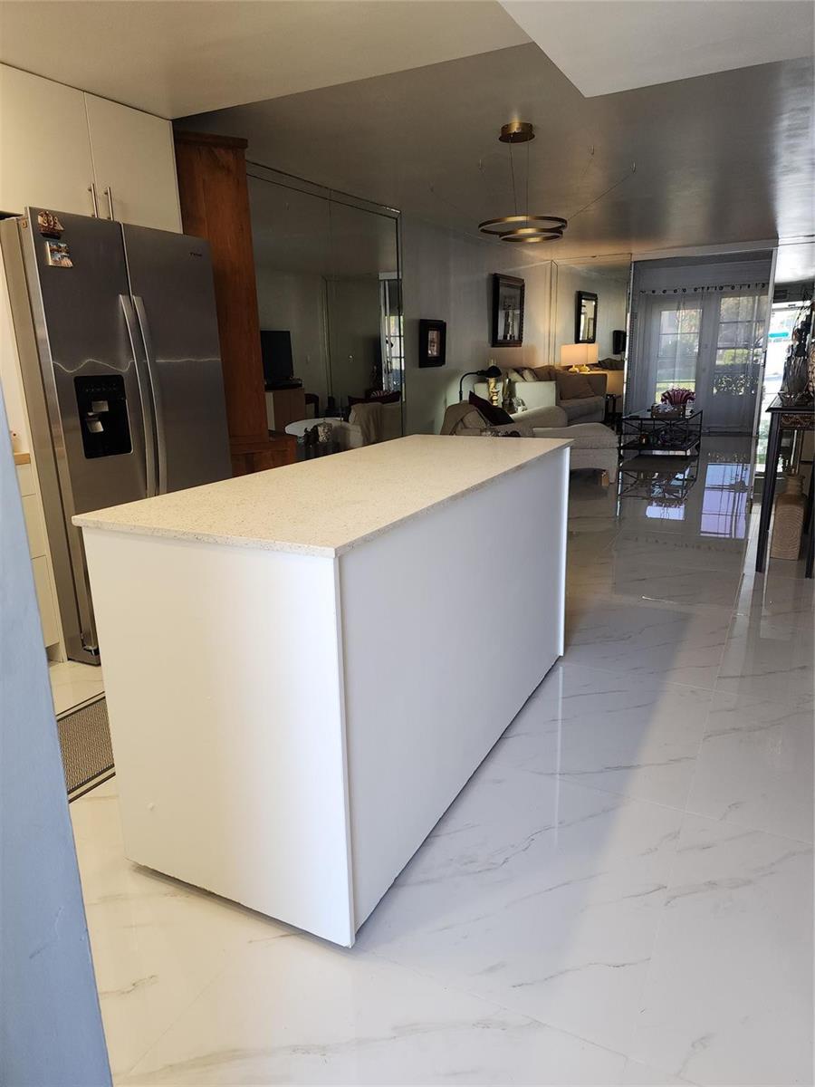 A kitchen island with a light countertop sits on a white marble floor — 700 SE 6th Avenue # 111, Deerfield Beach FL 33441, DEERFIELD BEACH, FL