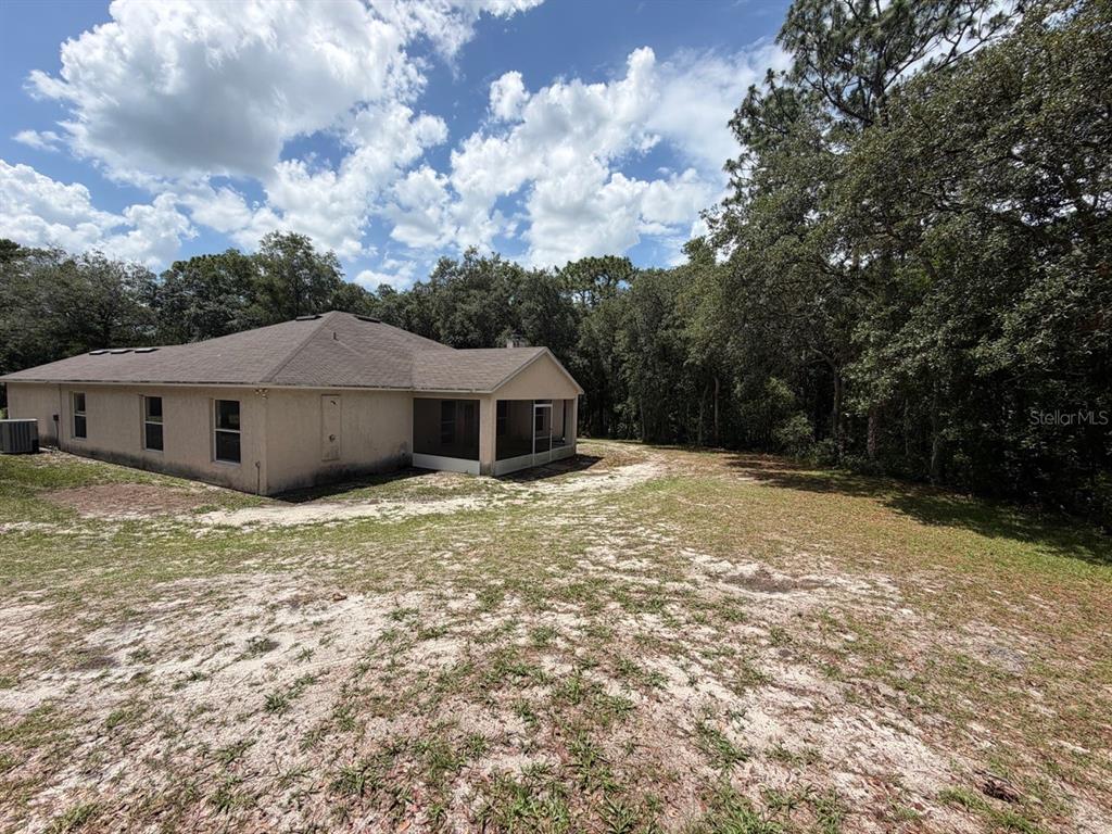 The exterior of a beige house with a screened-in porch sits on a sandy lot — 981 SEVILLA AVENUE, LAKE HELEN, FL