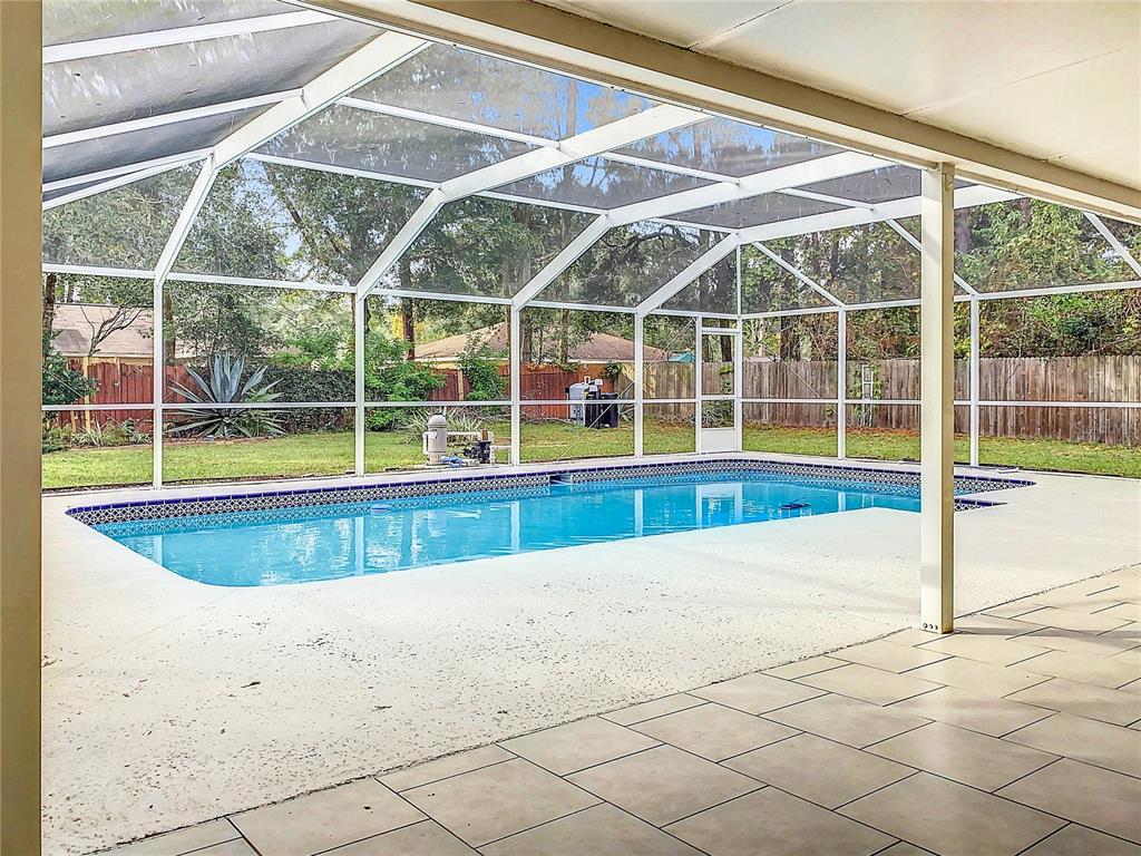 A single-story house with tan siding and a brown roof sits on a grassy lot — 6170 NW 57TH COURT, OCALA, FL