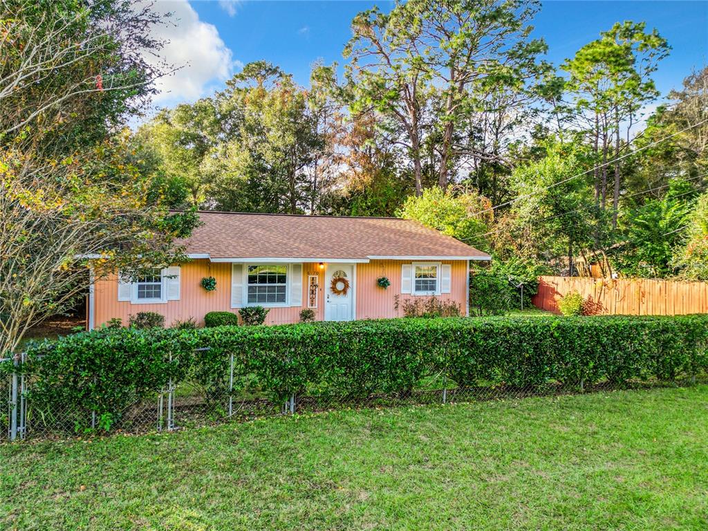 A screened-in swimming pool sits on a concrete patio behind a house with a fence — 6170 NW 57TH COURT, OCALA, FL