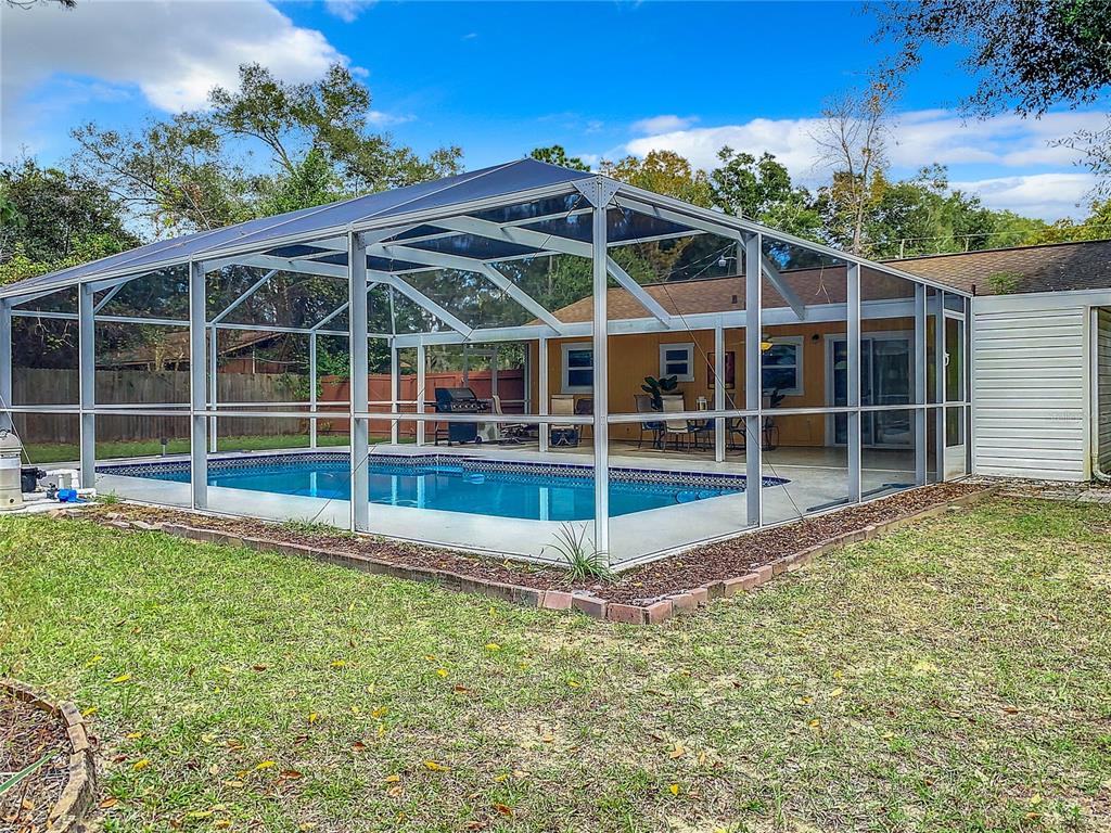 A rectangular swimming pool is enclosed by a white screen cage in a grassy backyard — 6170 NW 57TH COURT, OCALA, FL