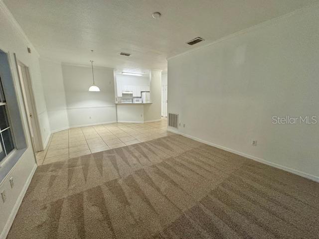 A carpeted living area transitions into a tiled dining space with a kitchen beyond — 3611 CONROY UNIT 818, ORLANDO, FL