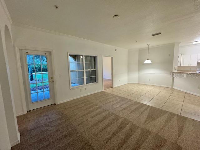 A living room with beige carpet transitions to a tiled dining area and kitchen — 3611 CONROY UNIT 818, ORLANDO, FL