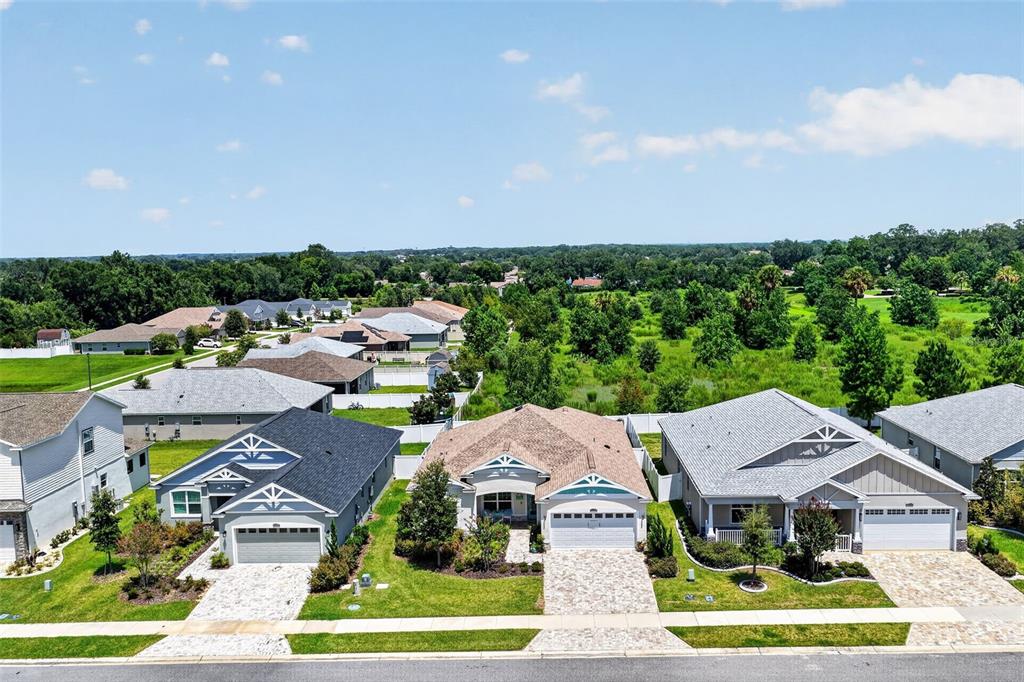 An aerial view shows three suburban houses with paved driveways and green lawns — 12615 NE 49TH DRIVE, OXFORD, FL