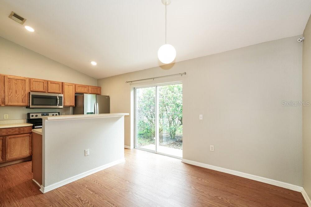 A kitchen with wood cabinets and a breakfast bar opens to a dining area — 3457 BELLERICAY LANE, LAND O LAKES, FL