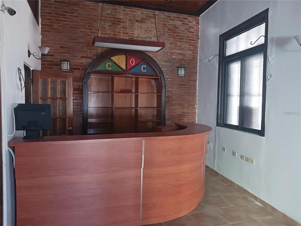 A wooden bar counter sits in front of a brick wall with built-in arched shelving — 101 CALLE REINA, PONCE, PR