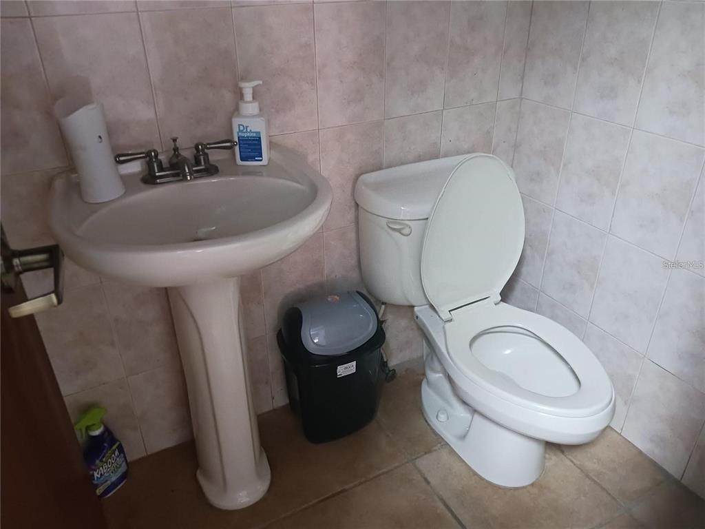 A small bathroom features a pedestal sink, a white toilet, and beige tiled walls — 101 CALLE REINA, PONCE, PR