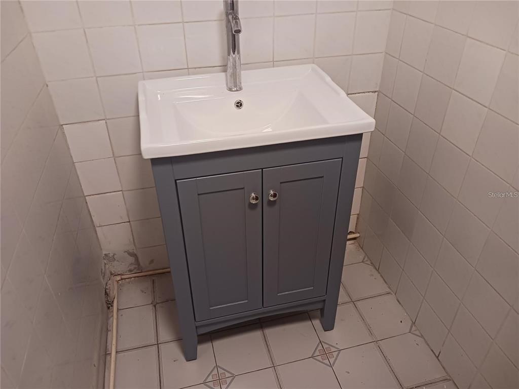 A gray vanity with a white sink sits against tiled walls in a bathroom — 101 CALLE REINA, PONCE, PR